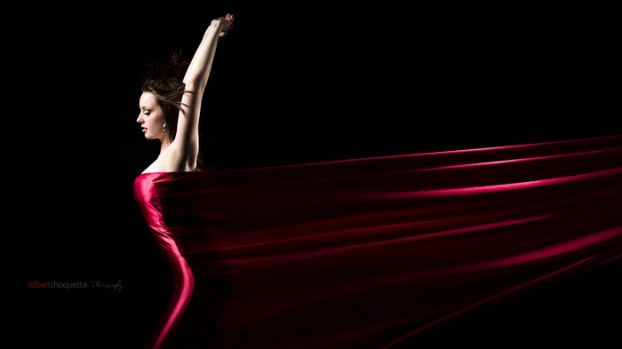 Woman in red fabric with arms raised