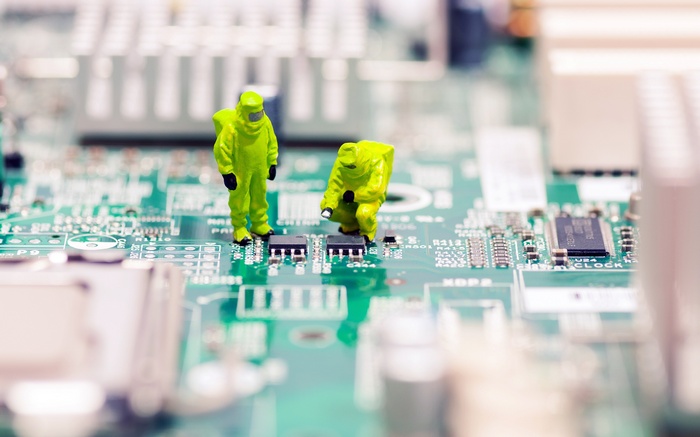 Miniature figures in hazmat suits on a computer motherboard