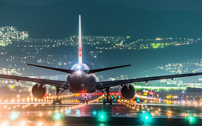 Airplane on a runway at night with cityscape in background