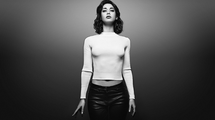 Lizzy Caplan in a white sweater and black pants