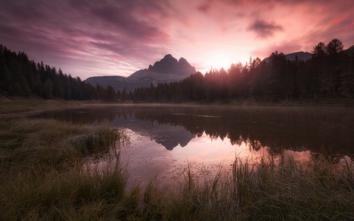 Mountain lake reflection at sunrise with pink clouds