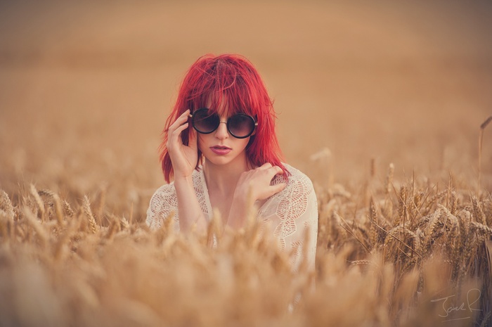 Redhead woman with sunglasses in a wheat field