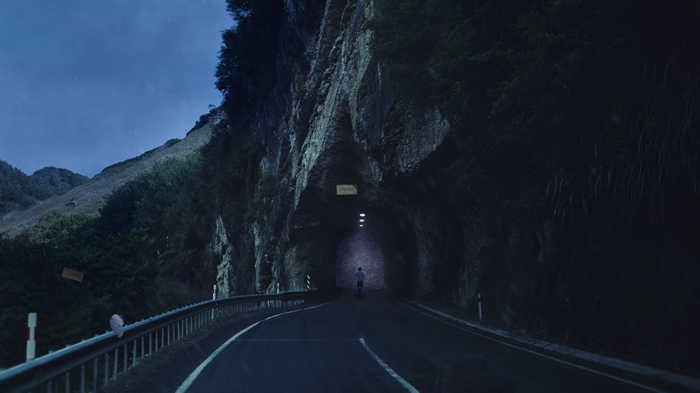 Person walking into a dark tunnel on a rainy night
