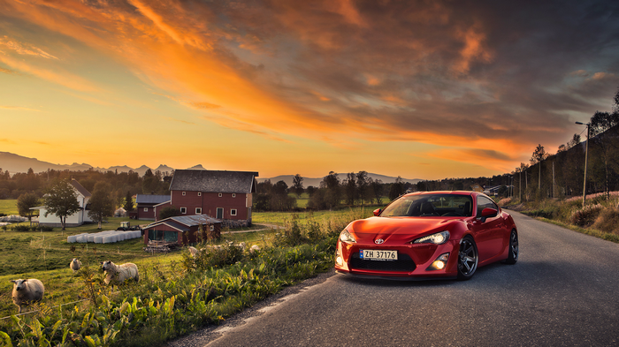 Red Toyota GT86 on a rural road at sunset