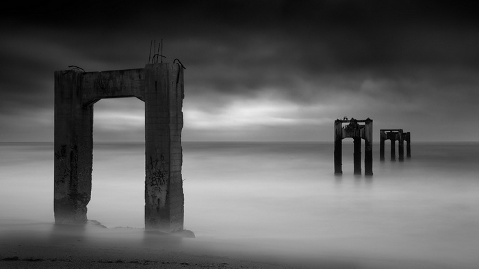 Ruined concrete structures on a beach with long exposure sea