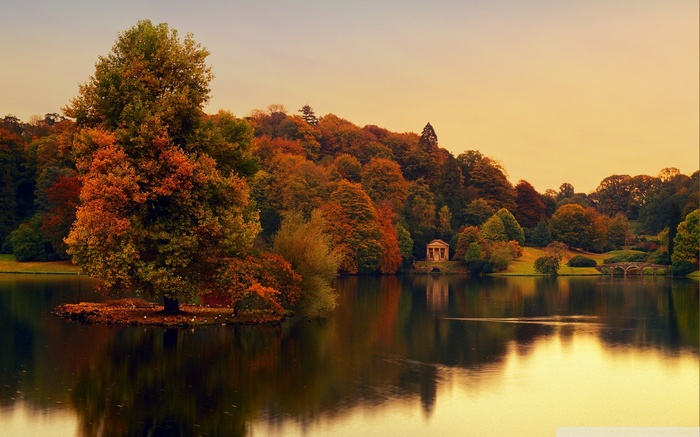 Autumn trees reflected in a lake with a temple and bridge