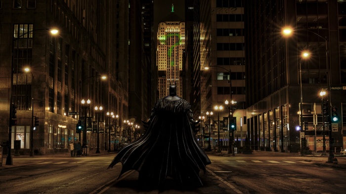 Batman standing in a dark city street at night
