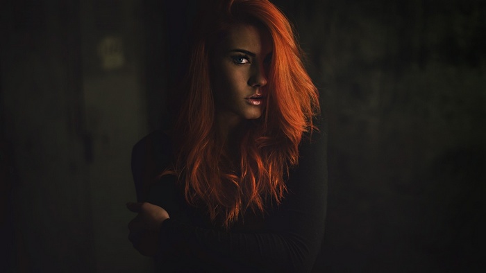 Woman with long red hair in a dark setting