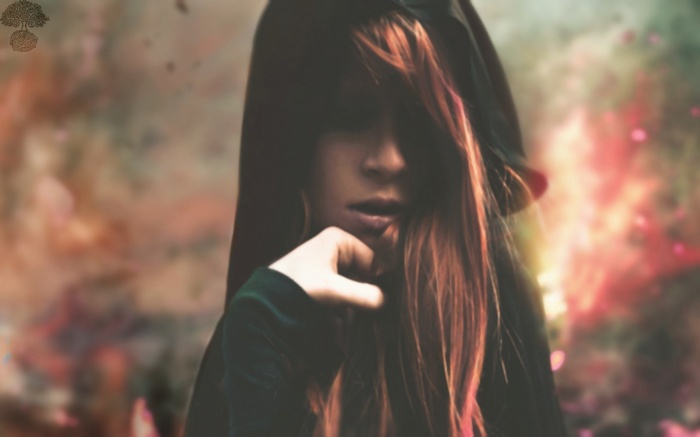 Woman with red hair wearing a dark hood