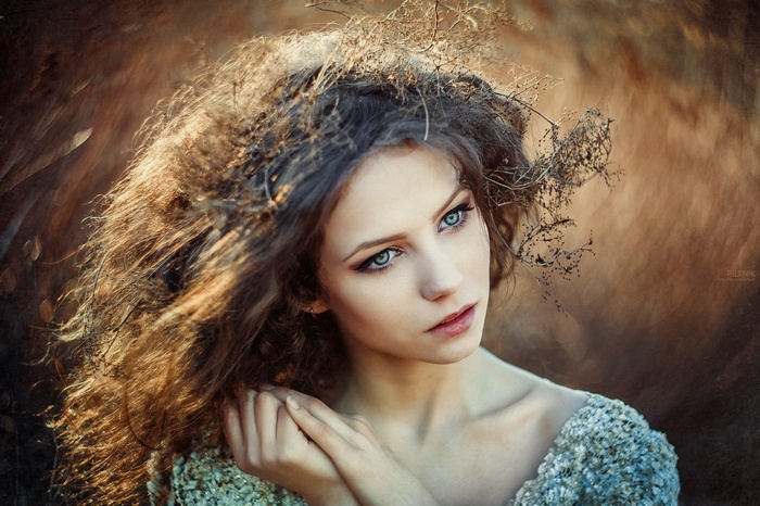 Woman with curly hair and a crown of twigs