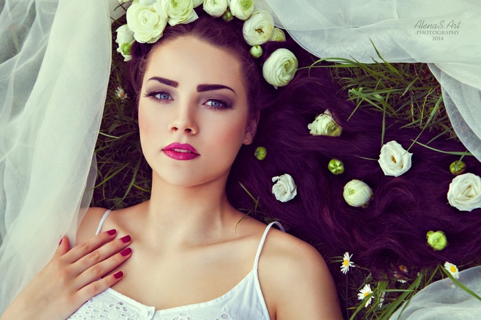 Woman with flowers in her hair lying in grass