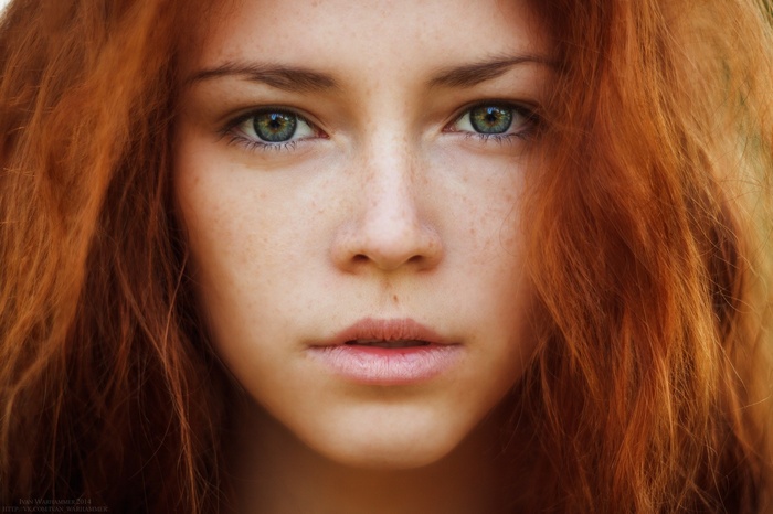 Close-up portrait of a young woman with red hair and freckles