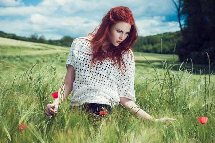 Redhead woman in a white top in a field of grass