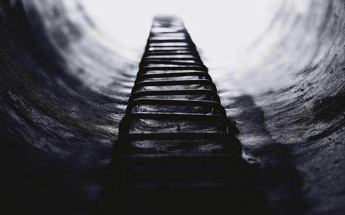 Metal ladder in a dark, curved tunnel