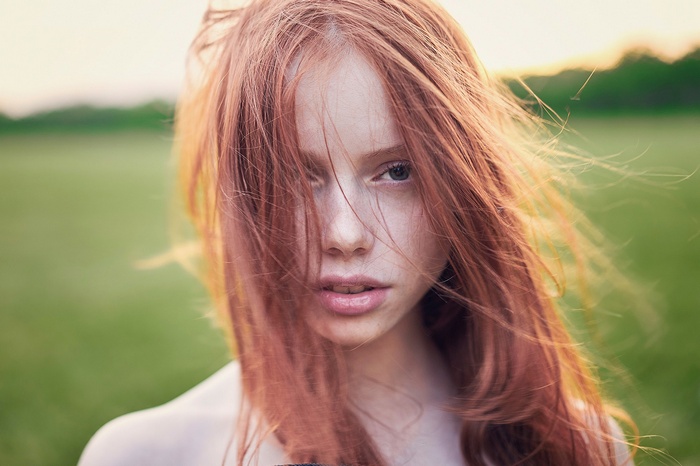 Young redhead woman with windblown hair outdoors
