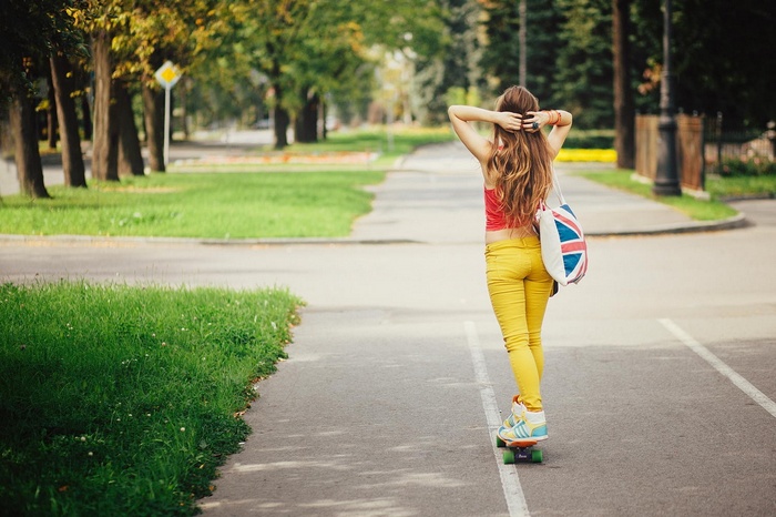 Woman skateboarding in a park with a Union Jack bag