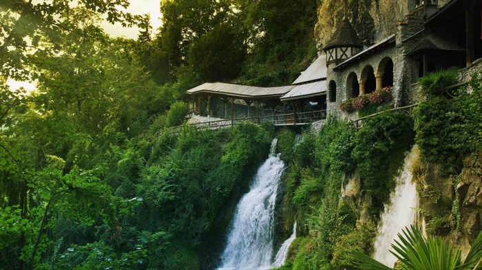 Building built into a cliff with a waterfall