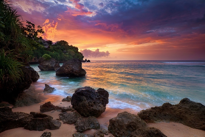 Tropical beach with rocks and colorful sunset sky in Bali