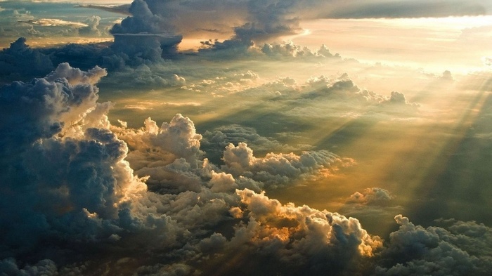 Sun rays piercing through dramatic clouds during sunset