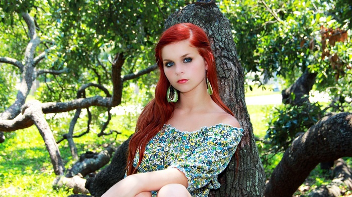 Redhead woman with blue eyes in a floral dress outdoors