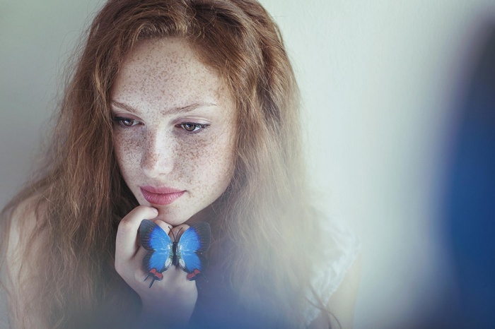 Portrait of a redhead woman with freckles and a butterfly