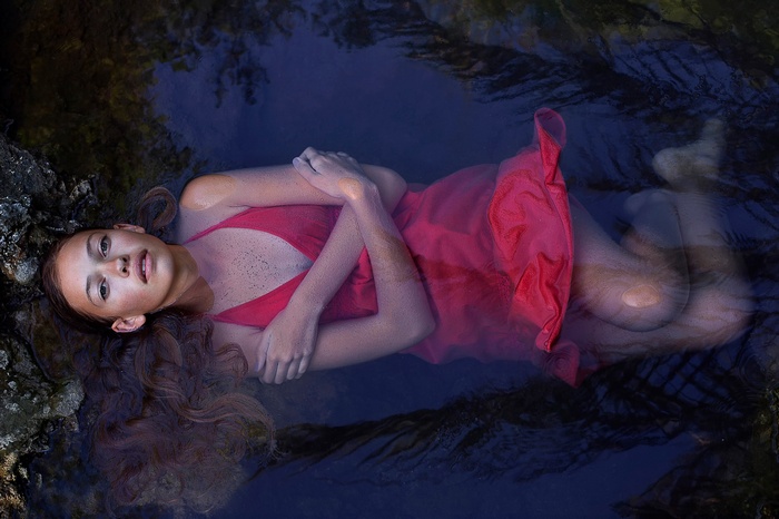 Woman in red dress floating in dark water