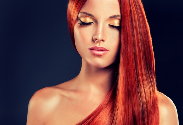 Woman with long red hair and gold makeup
