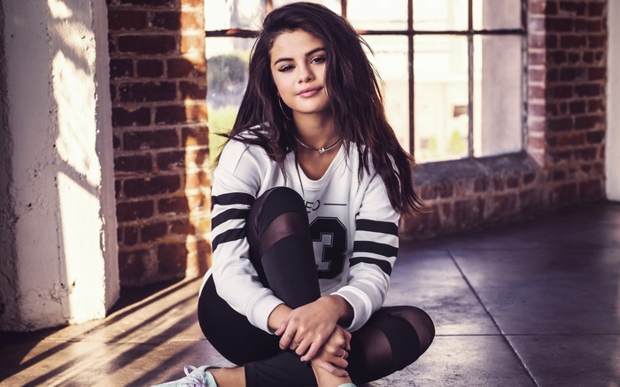 Selena Gomez sitting on the floor indoors