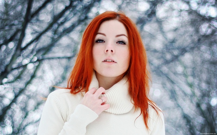 Redhead woman in white sweater in winter forest