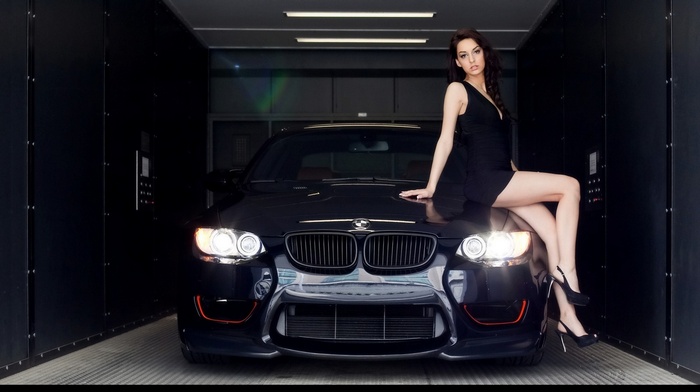 Woman sitting on a BMW car in a garage