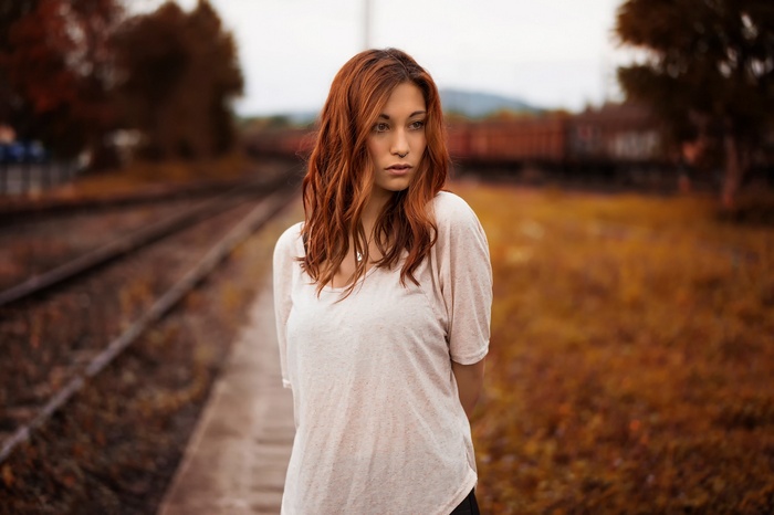 Woman with red hair standing by railway tracks