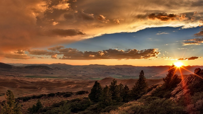 Sunset over a vast valley with rolling hills and trees