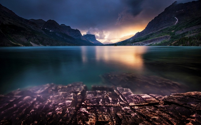 Sunset over a calm lake with mountains and rocks