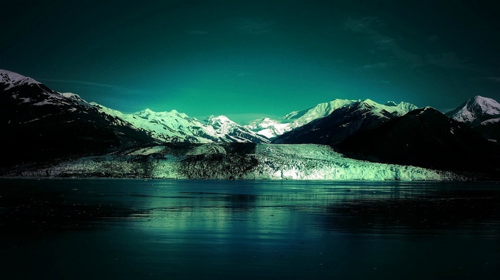 Snow-capped mountains and glacier over a dark lake