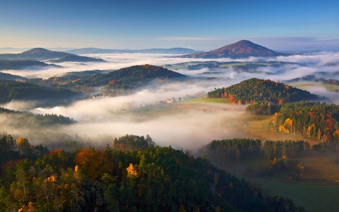 Misty mountains and forests in autumn morning light