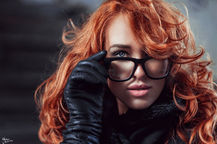 Woman with red hair and glasses wearing black gloves