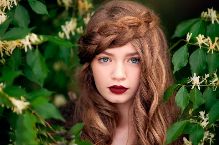 Woman with blue eyes and braided hair in foliage