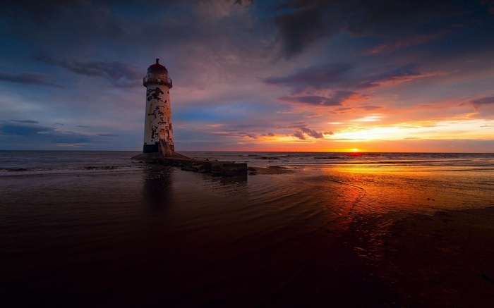 Lighthouse on a beach at sunset