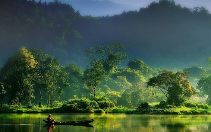 Fisherman in a boat on a misty river in Indonesia
