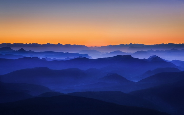 Misty mountains at sunrise with orange sky