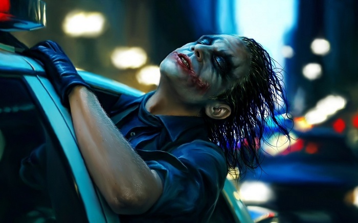 The Joker leaning out of a police car