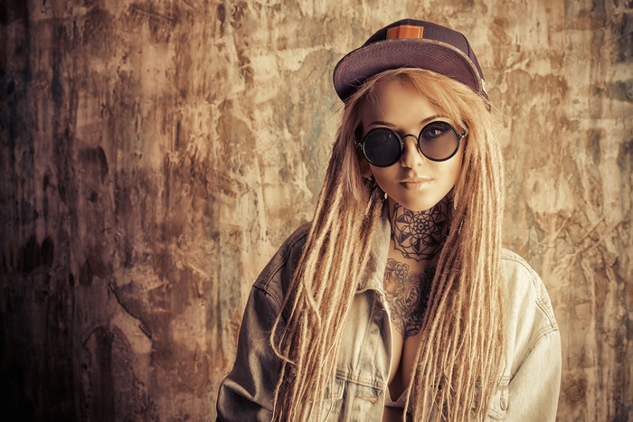 Woman with dreadlocks, tattoos, and glasses