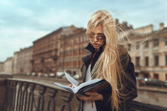 Blonde woman with glasses reading a book
