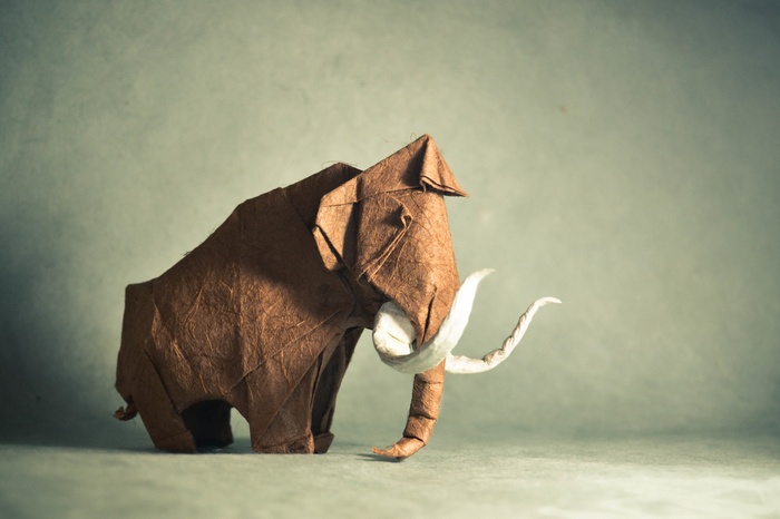 Brown origami mammoth with white tusks