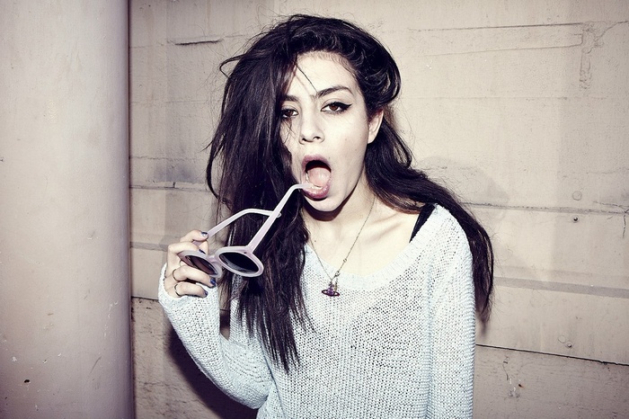Charli XCX with sunglasses in her mouth