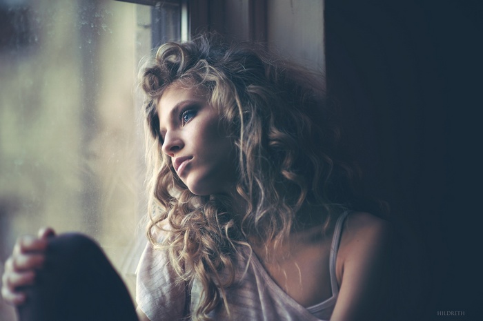 Woman with curly hair looking out a window