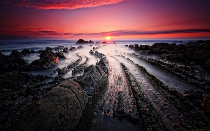 Sunset over rocky coastline with misty water