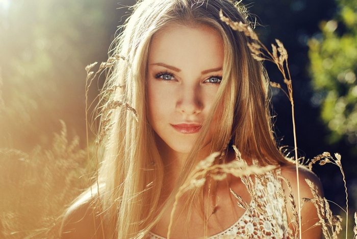Woman with blonde hair and blue eyes in a field