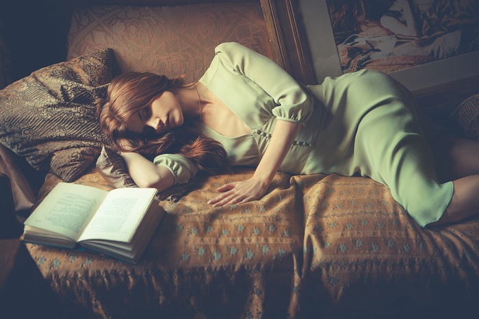Redhead woman sleeping on a couch with a book
