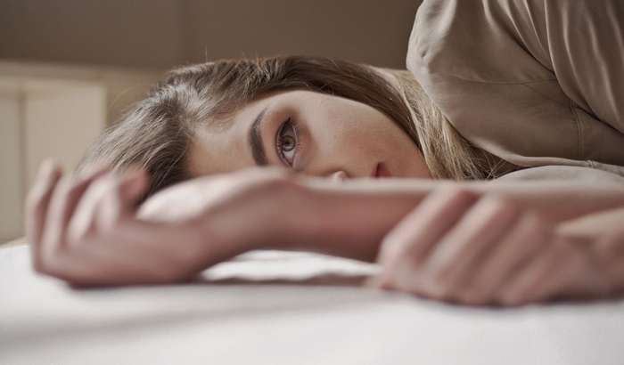 Woman lying down with arm across face